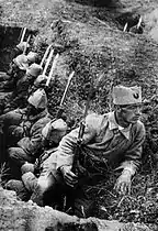 Soldiers in a trench, with one looking in a different direction