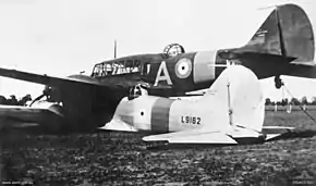 Rear three-quarter view of two military monoplanes lying wheels down on a field, one atop the other