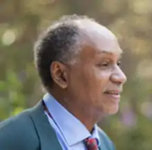 color headshot of an older black man, wearing a suit and facing right