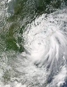 Satellite image of a ragged tropical cyclone, with a loosely defined eye and sprawling rainbands.