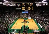 Interior of a basketball arena with the scoreboard and stands visible.