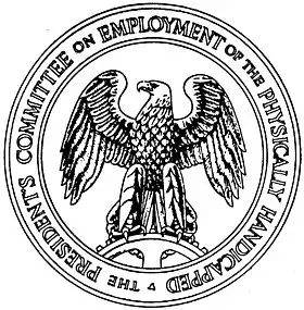 A round seal with the words "The President's Committee on Employment of the Physically Handicapped" around the edge. In the center is an eagle standing on a spur gear and facing to its right.