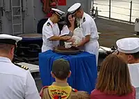 A baby is baptized with holy water from the ship's bell