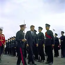 US President John F. Kennedy, escorted by a Bermuda Militia Artillery officer in Royal Artillery blue No. 1 Dress, inspects green-uniformed riflemen of the Bermuda Rifles in 1961