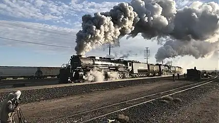 Two steam locomotives double heading and surrounded by railfans in the foreground