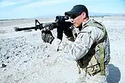 A US Navy SEAL aims his rifle with an attached LA-5C/PEQ as part of the SOPMOD Kit.