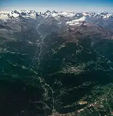 Airplane view of a wide valley and snow-capped mountains.