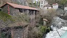 Autumn photo of a former cutlery factory building downstream from the Creux de l'enfer factory. The 2-storey brown shale stone building has just been partly restored, and the tiled roof is new, but there are no window frames yet.