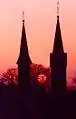 Moonset in May. In foreground at left the Catholic church, at right the Evangelical church, view towards the west