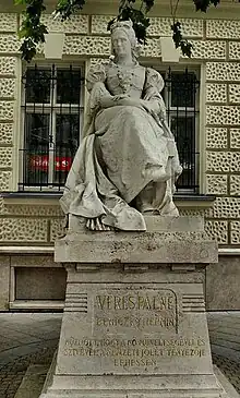 Stone sculpture of a seated woman on a pedestal carved with Hungarian text