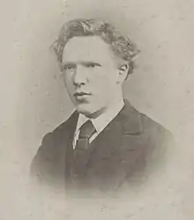  Head shot photo of the artist as a clean-shaven young man. He has thick, ill-kept, wavy hair, a high forehead, and deep-set eyes with a wary, watchful expression.