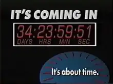 A television screenshot. On a black screen, from top: 1. The words IT'S COMING IN in a bold, white sans serif. 2. Inside a white box, a countdown showing days, hours, minutes and seconds. 3. In the lower right, a blue 3D circle with red elements suggesting the dial faces on a clock and, on top in white, the words "It's about time." in white