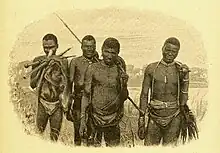 group of men standing in the open with spears and other traditional hunting gear