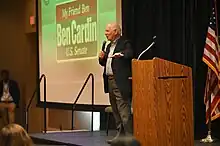 Cardin speaking on a stage with a "My Friend Ben Cardin for U.S. Senate" logo on a projector in the background