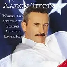 A Caucasian man with a moustache is shown, with the flag of the United States of America displayed faintly in the background