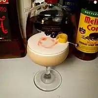 Image 4A whiskey sour, served in a coupe glass, is garnished with a spiral of lemon peel and two maraschino cherries on a cocktail pick, along with drops of bitters swirled into the foam (from egg white) atop the drink. (from Cocktail garnish)