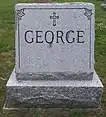 Grey granite stone engraved with the George family name and adorned with a cross