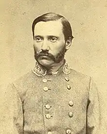 Black and white photograph of man with short hair, a mustache with connected sideburns wearing a gray uniform