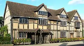 A two-story house with wattle and daub walls, a timber frame, and a steeply pitched roof