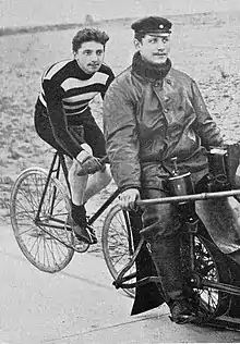 A male cyclist behind a pacemaking motorcycle during a race