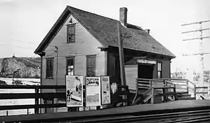 A two-story house next to an elevated railway line. The upper level of the house serves as a railway station.