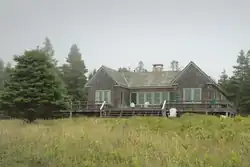 A house with seagrass in front, set against tall trees