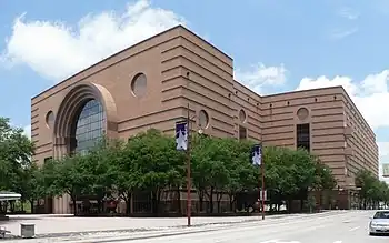 Low rise  granite building, composed of three large blocks with horizontal banding. It has a large,  glassed entrance that is rounded at the top.