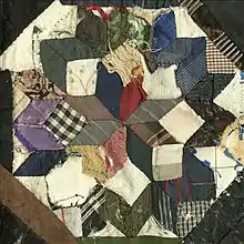 A fraying quilt with a geometric design.  The design is made of square and rhombic patches of different fabrics forming, altogether forming an octagon.