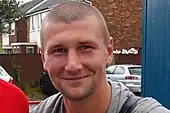 Head of a smiling white man with close-cropped hair.