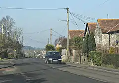 Residential housing along a road at the top of a hill with other buildings visible in the distance.