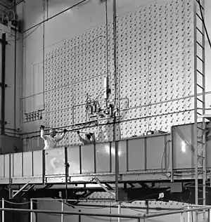 Workers load uranium slugs into the X-10 Graphite Reactor's concrete face.