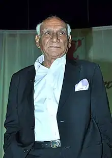 Yash Chopra is standing with his hands in his pockets, and looking away from the camera