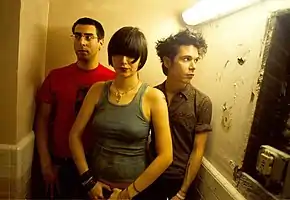 A woman and two men in a bright hallway.