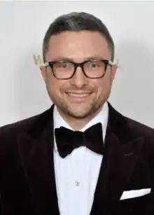 Zachary Weckstein wearing a dark suit and bowtie with white shirt, grinning at camera