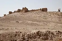 A ruinous stone wall in a desert landscape