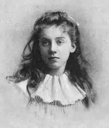 A young white woman, wearing hair long and loose, wearing a wide white circle collar.