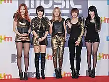 Image of 4Minute members smiling and wearing black and golden clothes