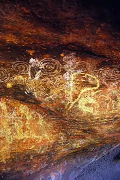 Wall of a cave covered in faded, earthy-coloured figures