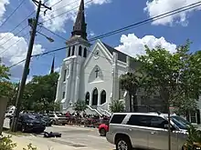 A large crowd of people gathered in front of a white-painted church