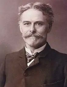 B & W photo/bust portrait of Edward Drinker Cope, paleontologist, c. 1985, in middle age with grey hair, mustache and chin puff; wearing a dark coat, soft bow tie and a slight smile.