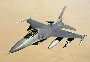 Airplane flying over desert, carrying fuel and weapons