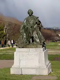 Bronze statue of Buffon wearing a ruffled shirt and a long coat, holding a bird with wings spread.