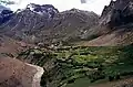 Farmland in Kargil lies straddled below the mountains and above a flowing stream.