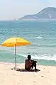 A man sitting under beach parasol.