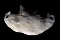 An irregularly shaped body is half illuminated from the bottom. The terminator runs from the left to right. The surface is covered by numerous craters.