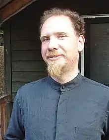 Peter Eckersley standing, wearing a grey button-down shirt, smiling slightly.