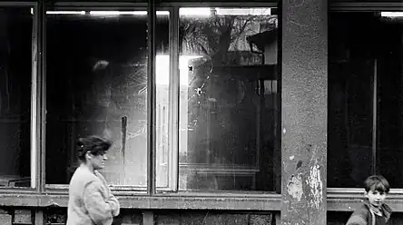 A mother and child walk along a street that Serbian soldiers have sniped