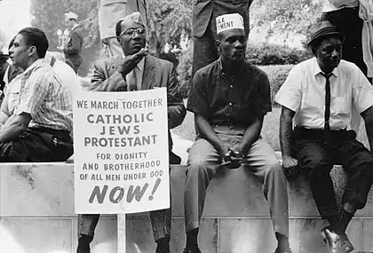 A protester holds a sign saying "We march together!"