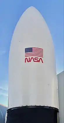 Photograph of a white nose cone with NASA worm logo and US flag