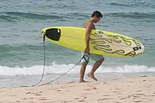 A surfer carrying his surfboard.